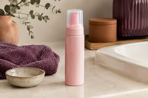 Mousse bouclante rose Activilong mise en scène dans une salle de bain lumineuse aux tons ivoire.